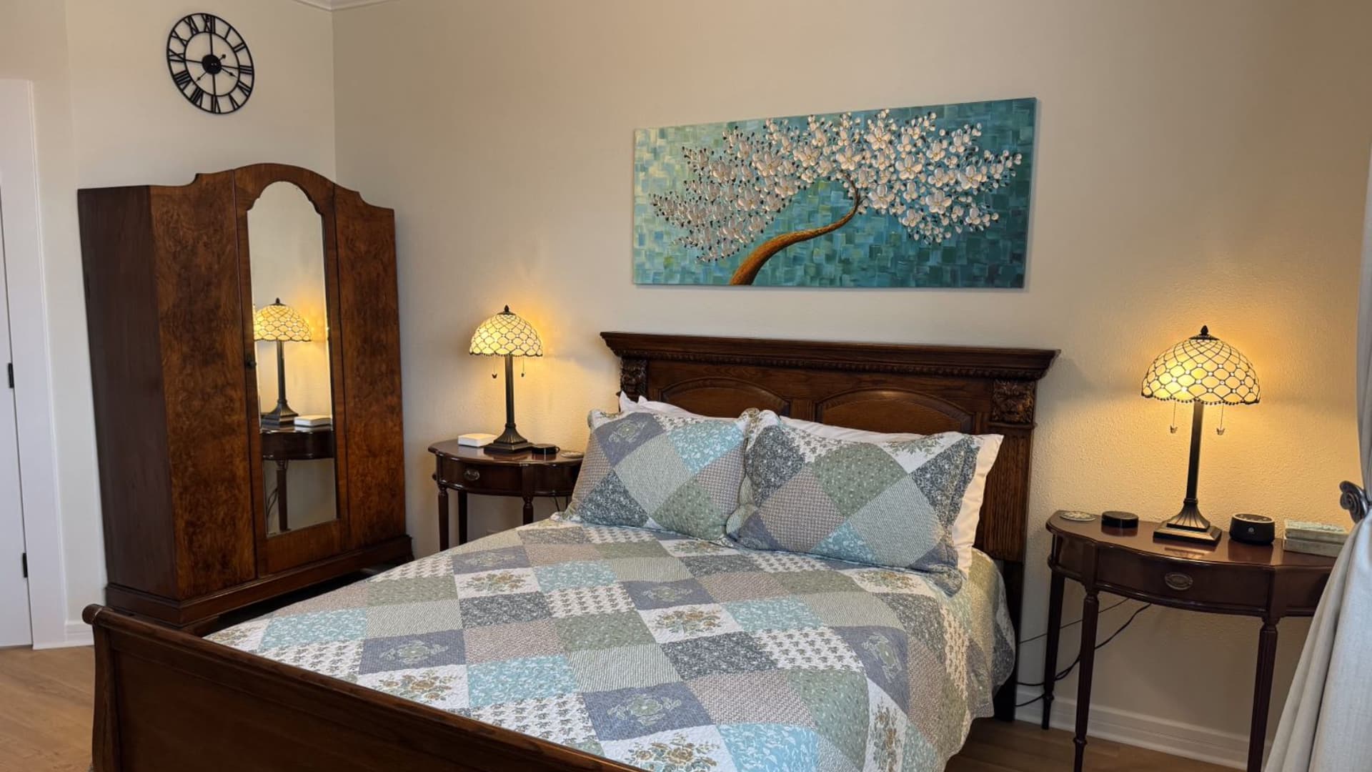 Cozy bedroom featuring a wooden bed, a patterned quilt, and decorative lamps.